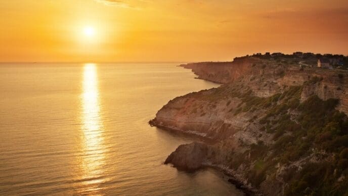 A scenic view of a rocky coastline at sunset.