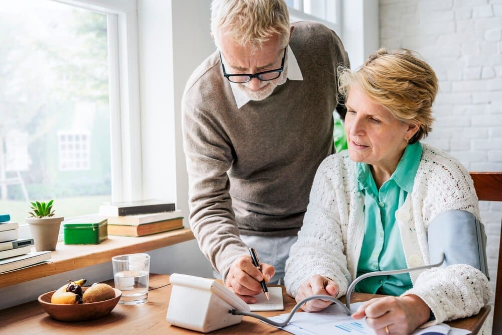 A senior adult has their blood pressure measured with a digital monitor.
