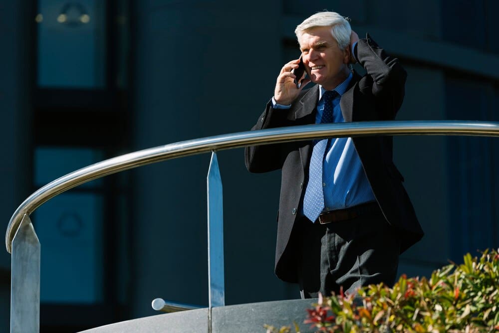 A senior businessman in a suit walks down a city street, likely symbolizing business success or experience.