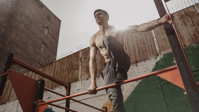 A shirtless athlete with a smartwatch works out outdoors, demonstrating calisthenics.