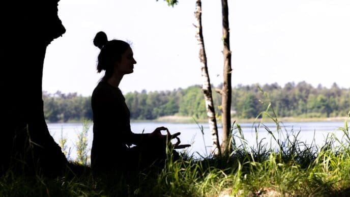 Silhouette of a woman sitting in a field, seen from the side.