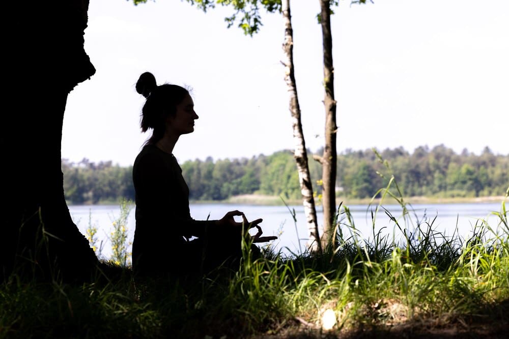 Silhouette of a woman sitting in a field, seen from the side.