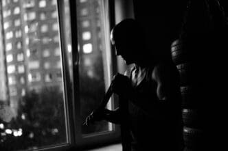 Silhouette of a muscular boxer wrapping tape around their arms in a dark gym, preparing for a fight.