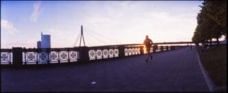 Silhouette of a woman walking across a bridge.