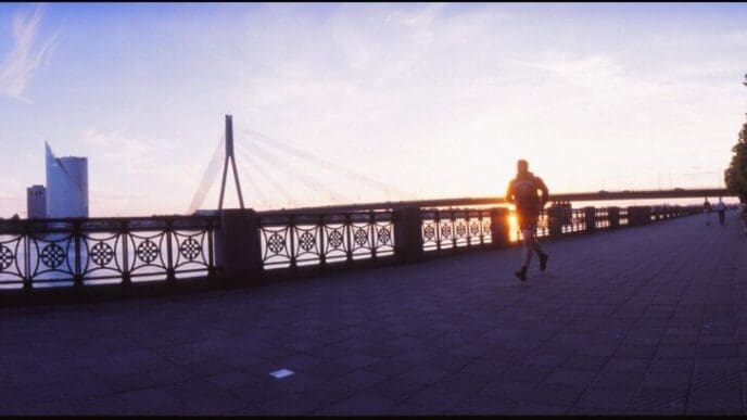 Silhouette of a woman walking across a bridge.