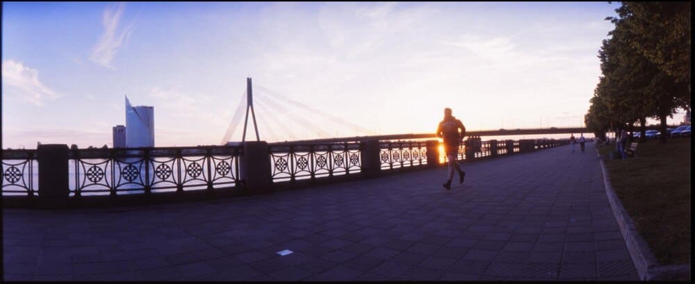 Silhouette of a woman walking across a bridge.