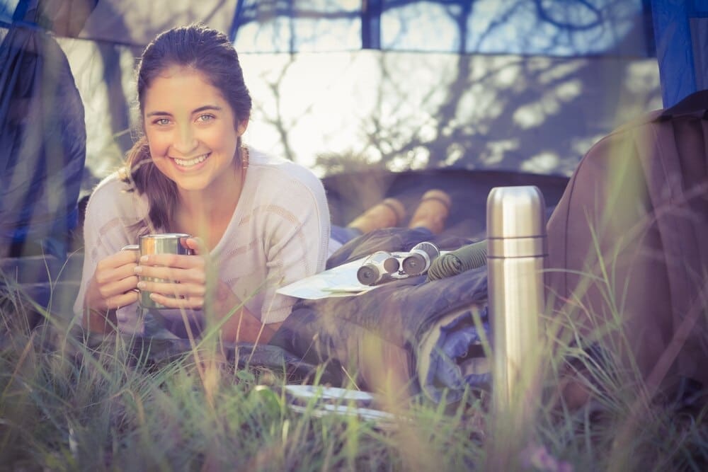 Smiling woman with brown hair reclines inside a tent.