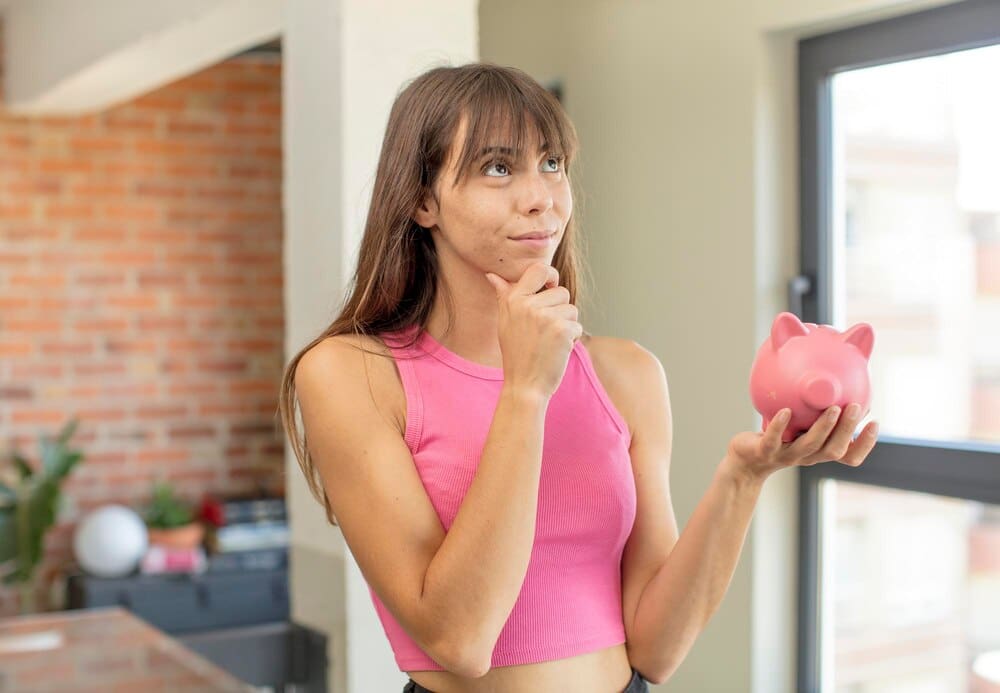 A person with a happy, confident expression smiles and rests their hand on their chin.