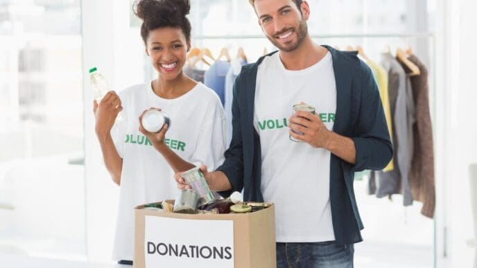A young couple smiles while holding a donation box.