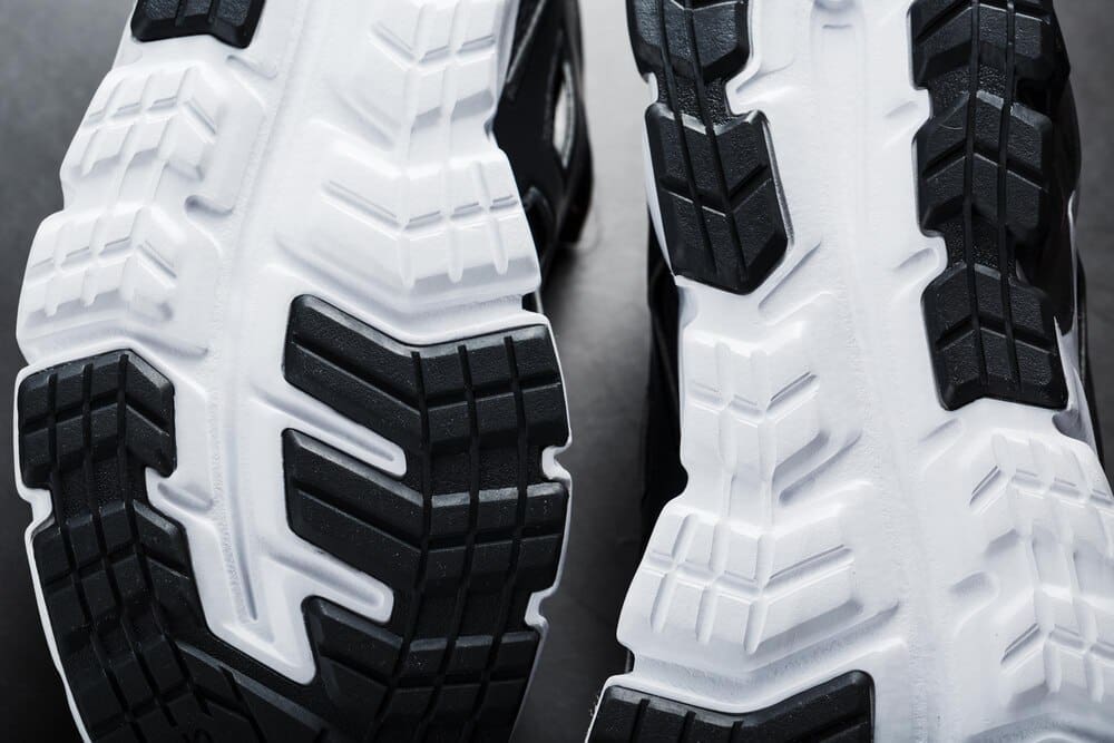 Close-up of the black and white sole of a running sneaker, showcasing sports technology.