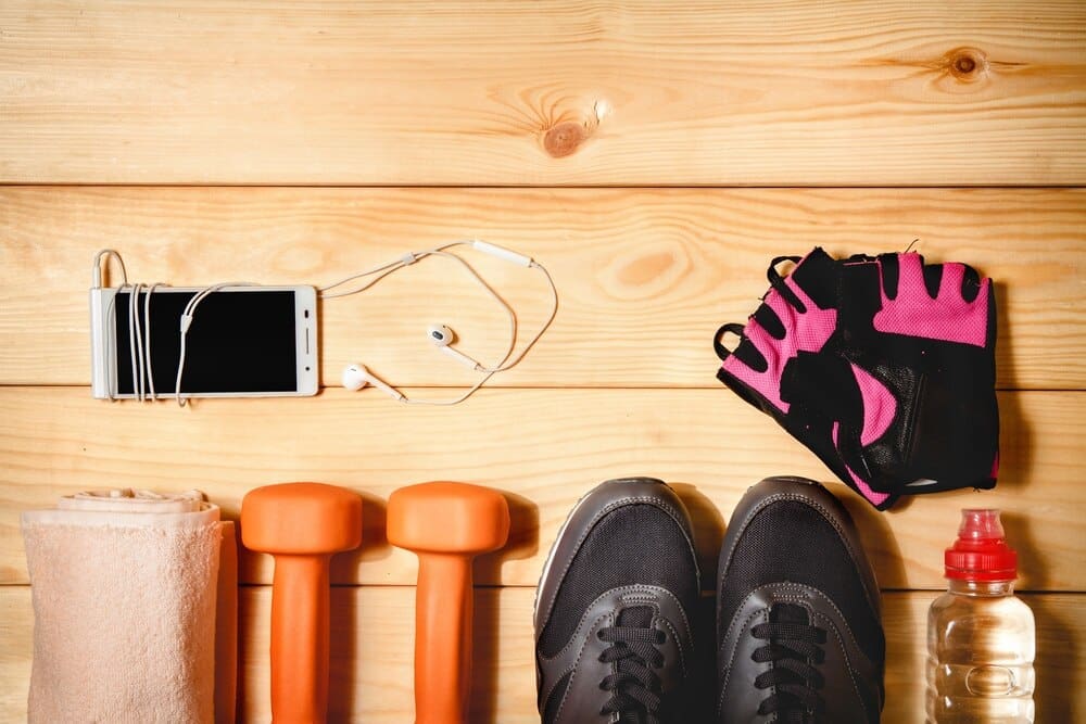 Sports equipment, including balls and cones, is arranged on a wooden floor.