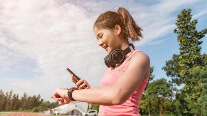 An Asian woman in athletic wear runs outdoors.