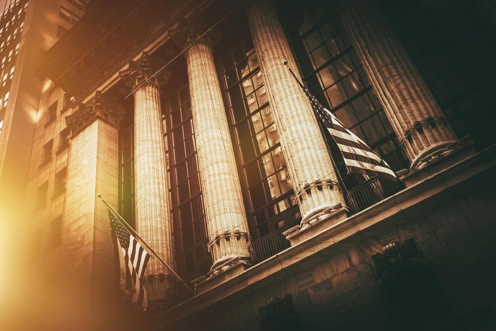 The New York Stock Exchange building features the American flag waving in front of its neoclassical facade.