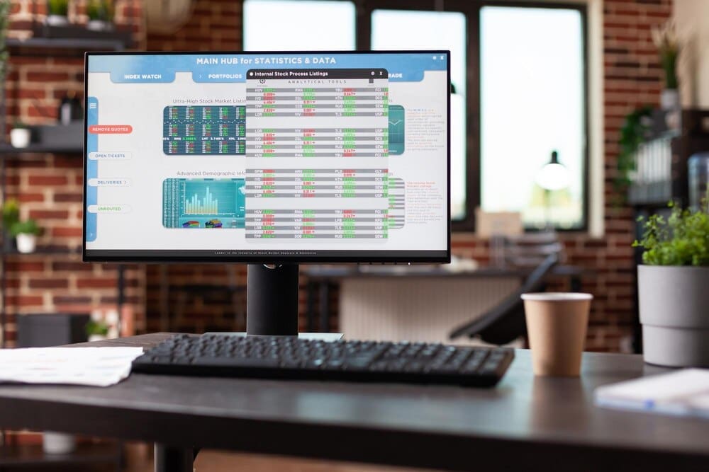 A computer monitor displays global stock market statistics and analysis in a modern office setting, suggesting online banking or cryptocurrency investment.