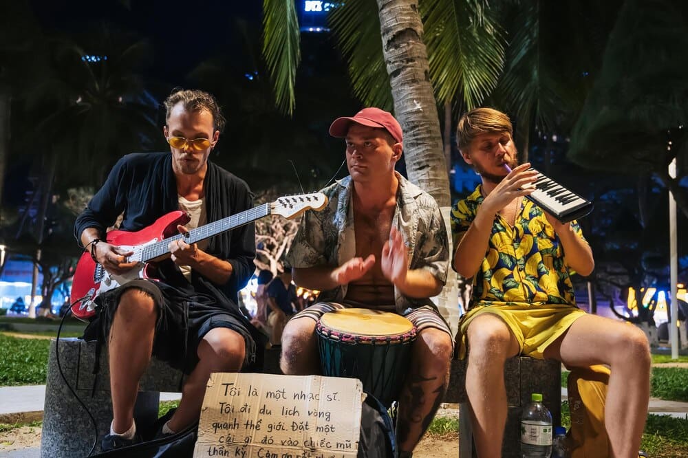 Street musicians prepare to perform in an alley in a park in Nha Trang, Vietnam, at dusk.