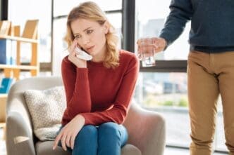 A young woman sits in an armchair, crying and looking unhappy while contemplating personal problems.