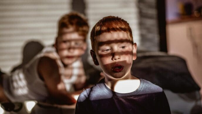 Two children, a boy and a girl, are illuminated by sunlight streaming through a window.