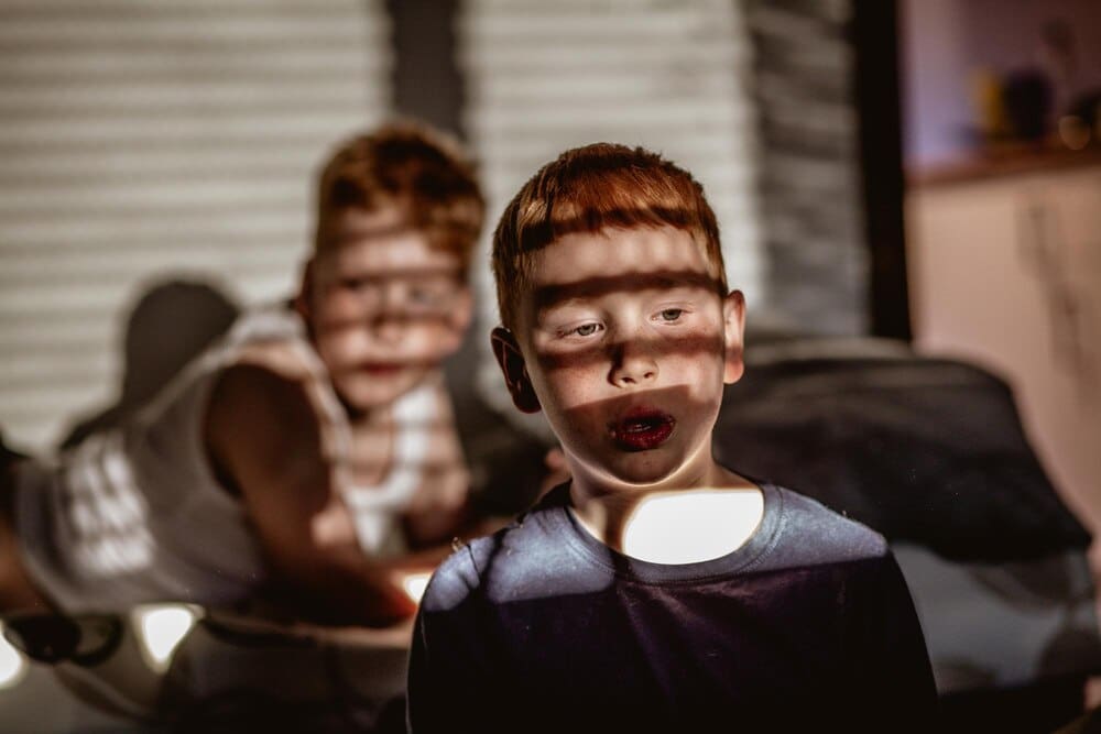 Two children, a boy and a girl, are illuminated by sunlight streaming through a window.