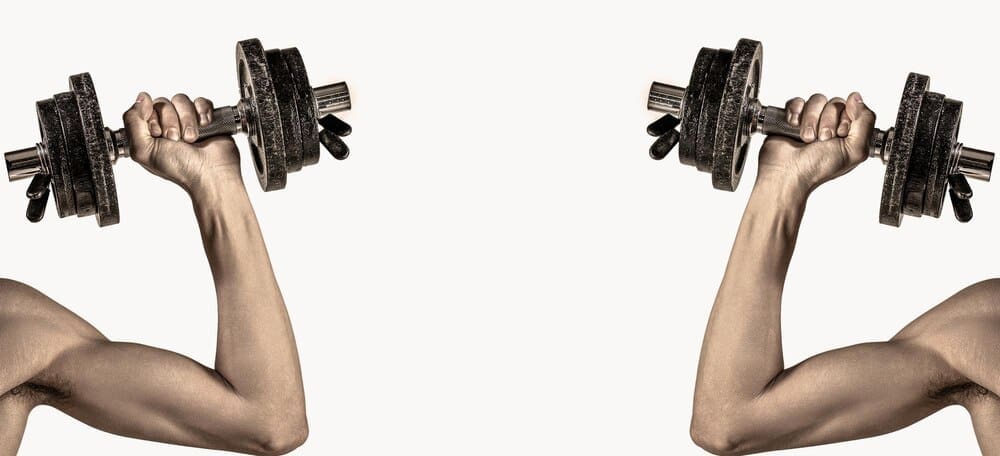 A thin man in athletic wear lifts a dumbbell, showcasing his bicep muscle.