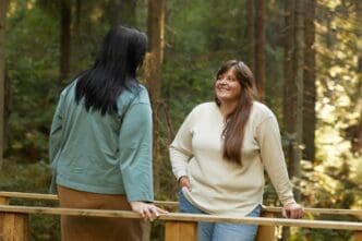 Two young friends converse while walking in a forest.