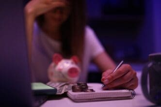 An upset woman leans over a family budget and scattered money.