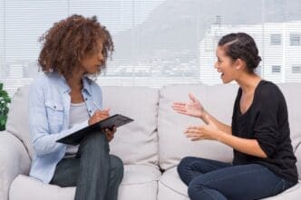 A woman with an upset expression speaks to a therapist.