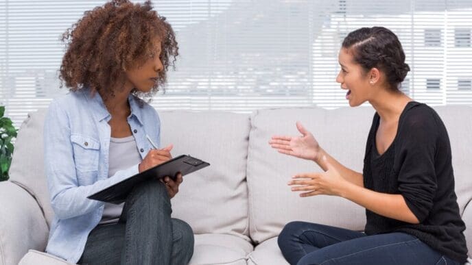 A woman with an upset expression speaks to a therapist.