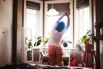 A woman stretches in her bedroom as part of her morning routine.