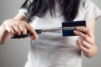 A woman uses scissors to cut a bank card in half.
