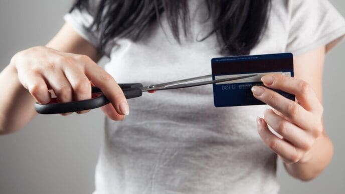 A woman uses scissors to cut a bank card in half.