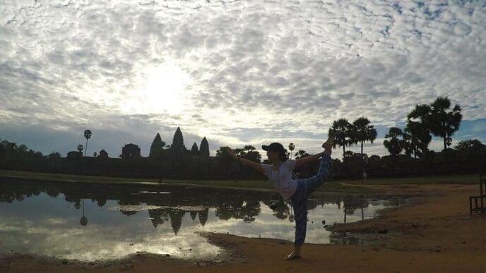 A woman exercises outdoors with a cloudy sky in the background.