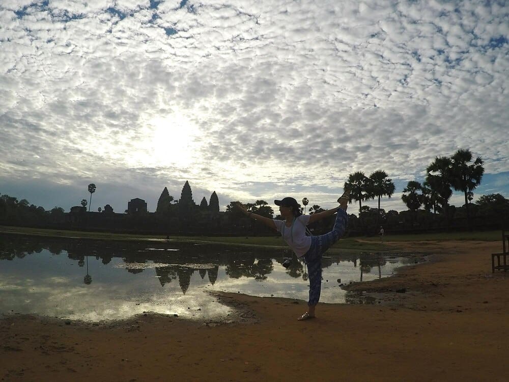 A woman exercises outdoors with a cloudy sky in the background.