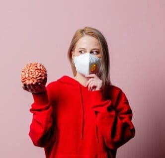 A woman wearing an FFP2 face mask holds a human brain.