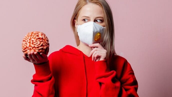 A woman wearing an FFP2 face mask holds a human brain.