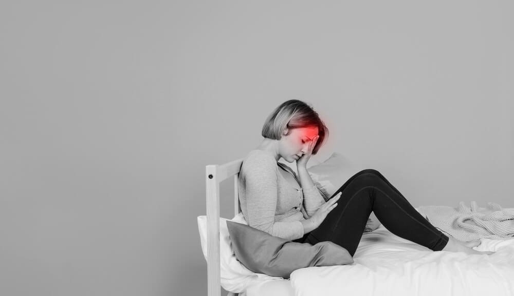 A woman with a pained expression holds her head.