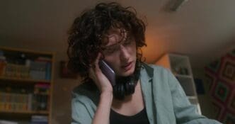 A woman is smiling and speaking on a cell phone while standing in a home.