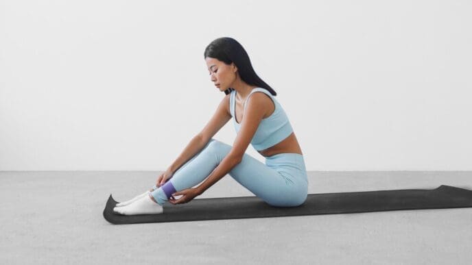A woman in athletic wear practices a sport on a black yoga mat.