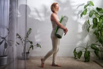 A woman practices yoga on a mat indoors, embodying a healthy lifestyle in a peaceful setting.