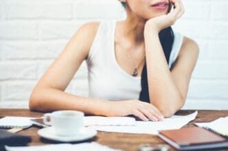 A woman is seated and focused on reading several documents.