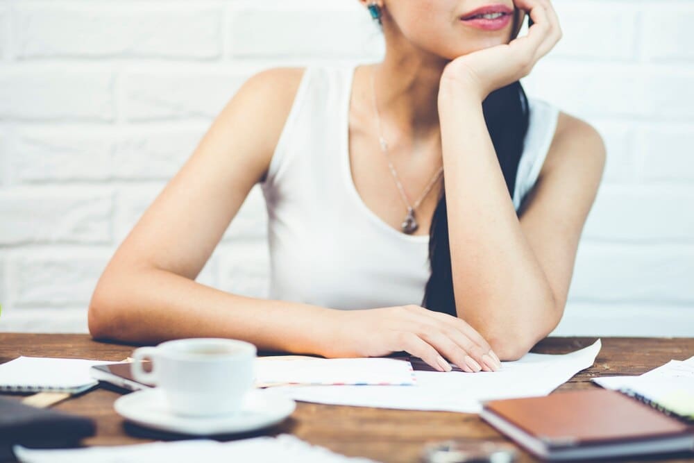 A woman is seated and focused on reading several documents.