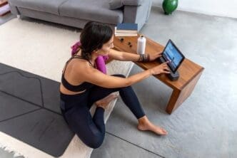 A woman rests on a yoga mat after completing an online yoga session in her home.