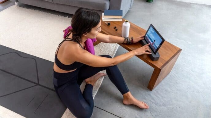 A woman rests on a yoga mat after completing an online yoga session in her home.