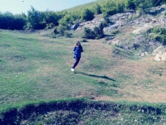 A woman runs across a grassy field.