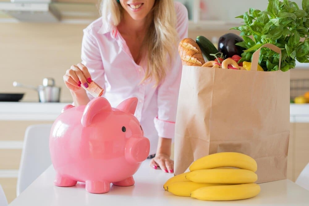 A woman smiles while using a tablet in a shopping cart, likely comparing prices or using coupons.