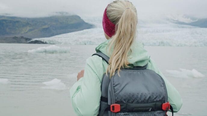 A woman stands near the Fjallsarlon glacial lagoon, gazing at the icebergs floating in the water.