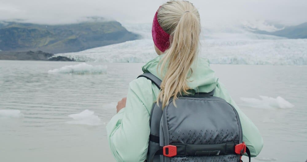 A woman stands near the Fjallsarlon glacial lagoon, gazing at the icebergs floating in the water.