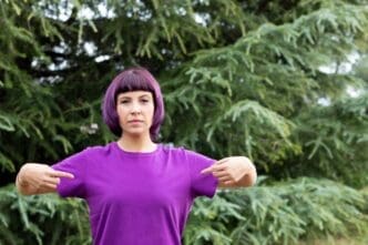 A woman with purple hair is wearing a t-shirt.
