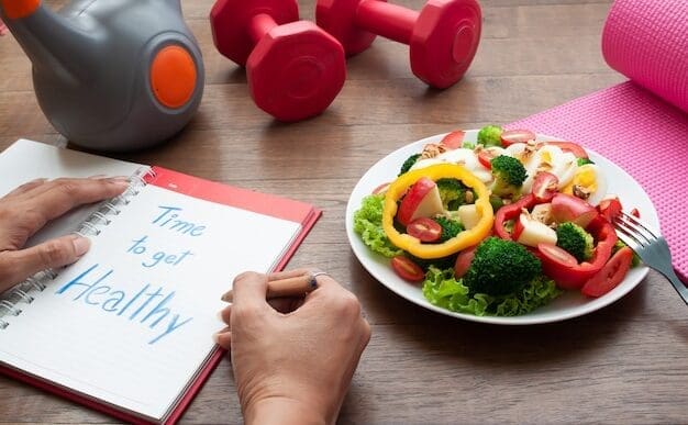 A woman writes in a diary at a table with a salad and fitness equipment.