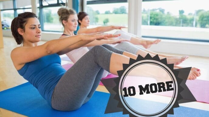 A group of women practice the boat pose in a yoga class, with a badge visible in the background.