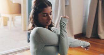 A woman stretches on a living room floor, practicing yoga for physical and mental wellness.